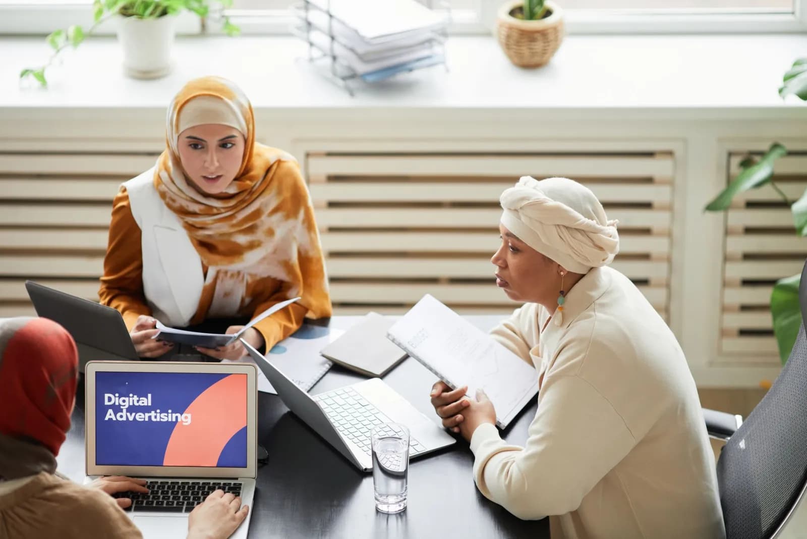 Tre kollegor som planerar digital marknadsföring vid ett bord med laptoper