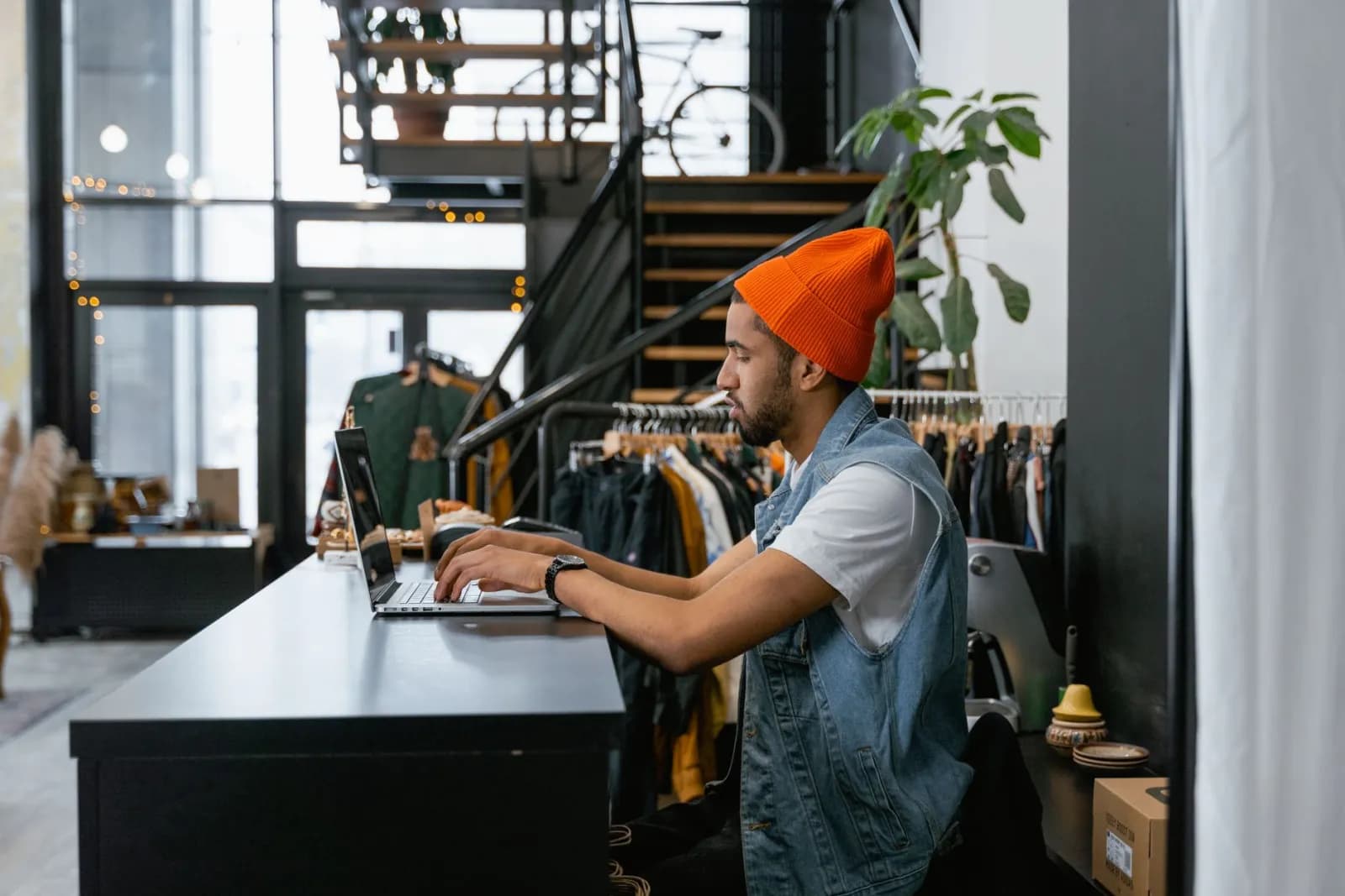 A clothing store employee typing on a laptop at the shop counter