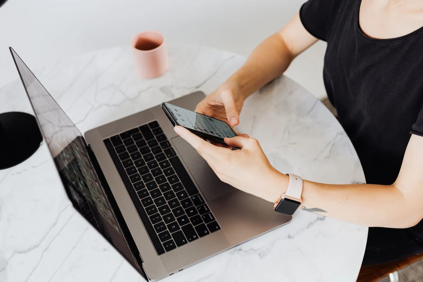 En kvinna planerar Instagram-inlägg vid en laptop med mobilen bredvid