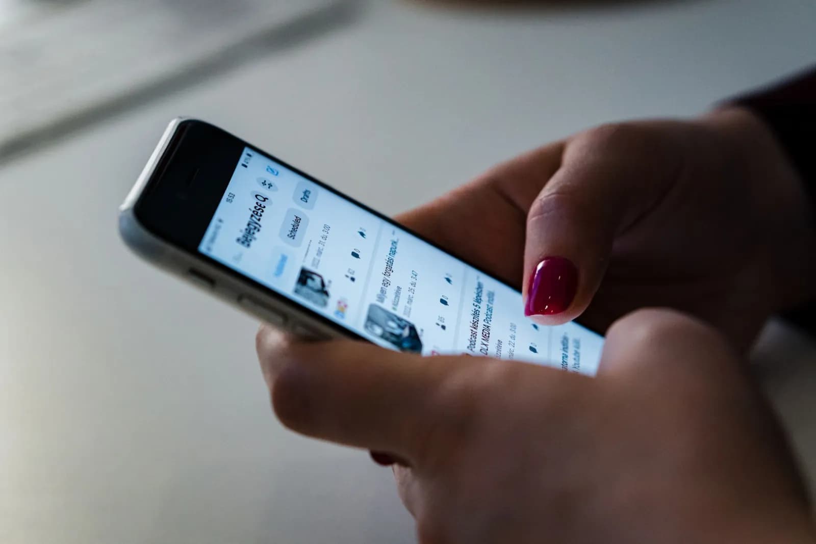 En hånd holder en smartphone og scroller på sociale medier